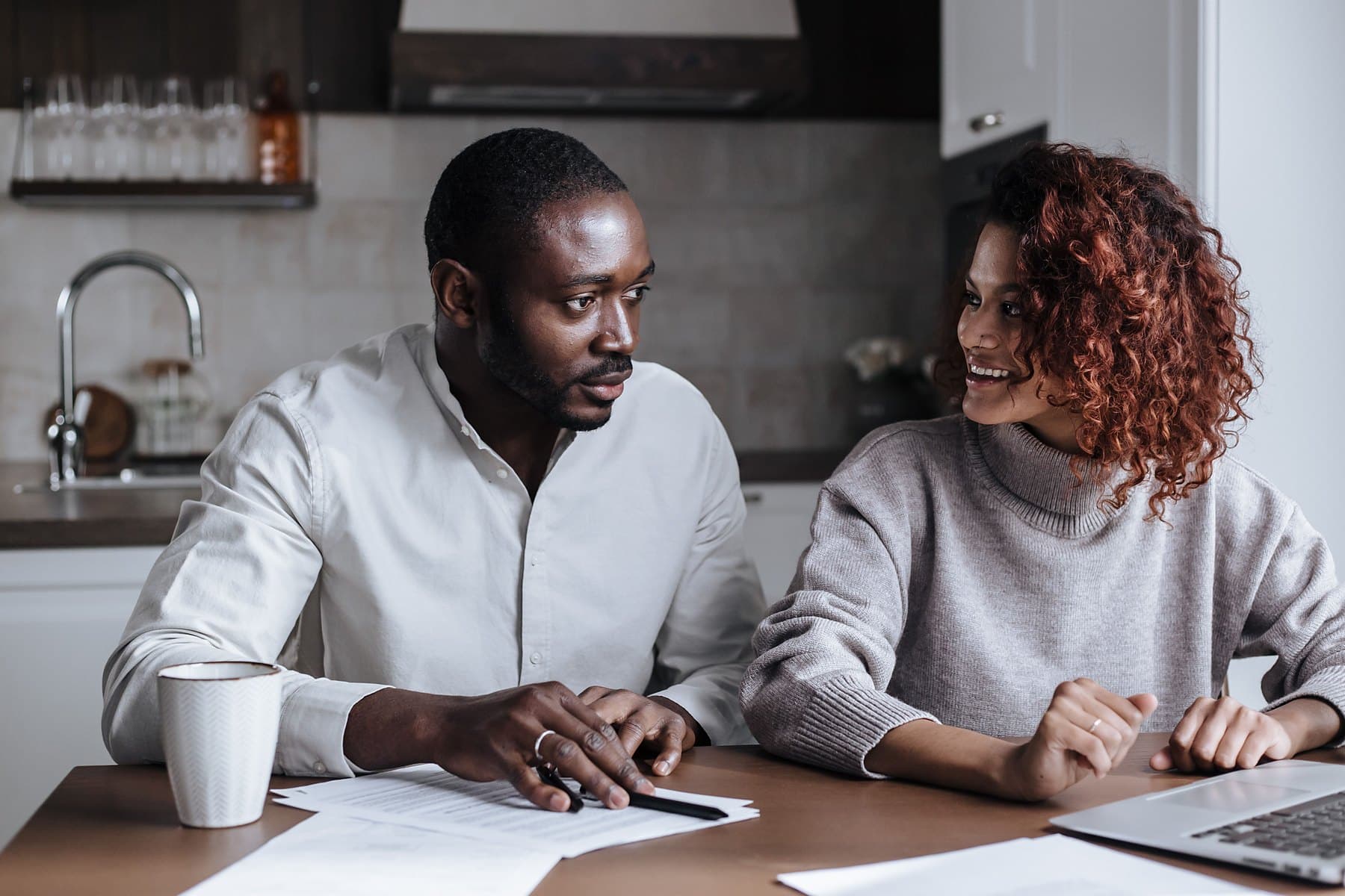 A couple reviewing paperwork and a laptop together at their kitchen table