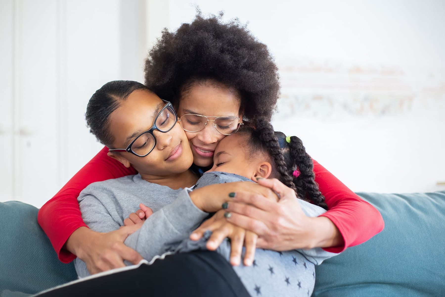 A mother embracing her two daughters in a close family hug